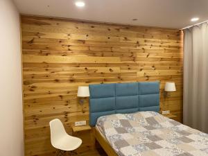 1 dormitorio con pared de madera, cama y silla en Apartament z ogrodem, en Starogard Gdański