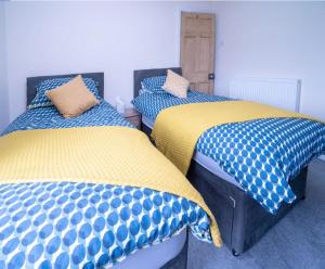 two beds in a room with blue and yellow at Quaint house in a beautiful rural setting in Froghall