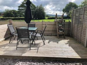 un patio con mesa, sillas y sombrilla en Quaint house in a beautiful rural setting, en Froghall