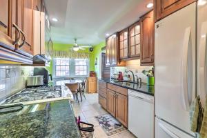 a kitchen with wooden cabinets and a white refrigerator at Yeadon Townhome with Porch, 7 Mi to Center City in Drexel Hill