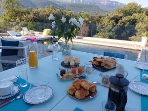 a blue table with food and drinks and a pool at Chez Herve et Lydie in Nans-les-Pins