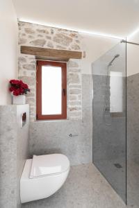 La salle de bains est pourvue de toilettes blanches et d'une douche en verre. dans l'établissement Kampus Luxury Villas, à Tríkala