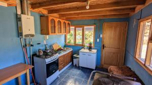 uma pequena cozinha com paredes azuis e um fogão em Cabaña el Coiron em Cochrane