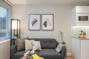 uma sala de estar com um sofá e quadros na parede em Westfield Apartment 2 Bedroom near Notting Hill em Londres