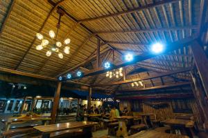 a restaurant with wooden tables and a ceiling with lights at Bamboo Paraiso Resort at Bolo Beach in Alaminos