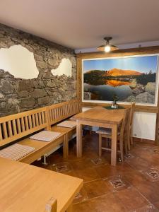 a restaurant with wooden tables and a stone wall at Penzion Brnenka in Špindlerův Mlýn