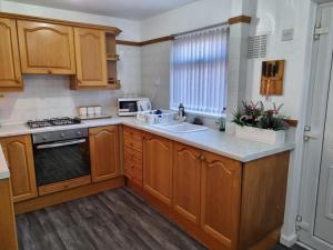 a kitchen with wooden cabinets and a sink at Modern 2-Bed Home - Private Garden Parking & WiFi in Leeds +16 photos