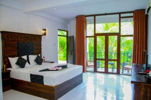 a bedroom with a bed and a large window at Manike Lodge Habarana in Habarana