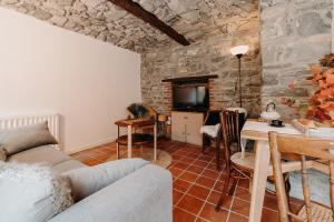 a living room with a couch and a table and a tv at Tiny stone in Maredret