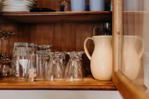 a shelf with glasses and a white vase on it at Tiny stone in Maredret