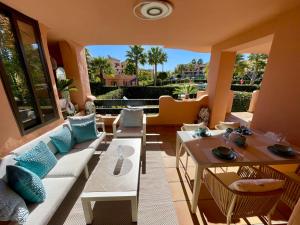 a living room with a couch and tables at Casares Beach Golf Apartment With Private Garden Direct Pool Access in Casares