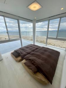 a bedroom with a large bed in front of the beach at Luxury Villa Saitozaki UMIHOTARU in Fukuoka