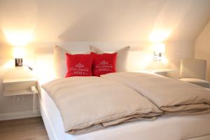 a white bed with two red pillows on it at Fürst Bismarck Mühle in Aumühle