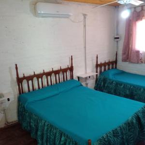 a bedroom with two beds with blue sheets and a window at Cabaña La Calandria in San José del Rincón