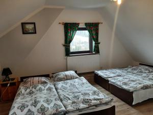 2 Betten in einem Dachzimmer mit Fenster in der Unterkunft Agroturystyka U Misia in Niedźwiedź