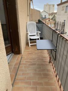 Biały fotel i stół na balkonie w obiekcie Confortable studio bord de mer w mieście Canet-en-Roussillon