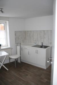 a white kitchen with a sink and a table at Citypension Melsungen in Melsungen