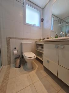 a bathroom with a toilet and a sink and a window at Riviera São Lourenço Excelente Apartamento e Local in Riviera de São Lourenço