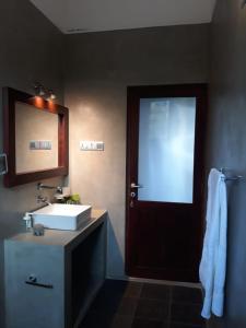 baño con lavabo y puerta con espejo en Mario River Villa en Ambalangoda