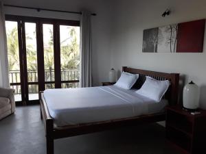 een slaapkamer met een bed en een groot raam bij Mario River Villa in Ambalangoda