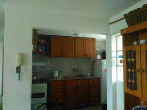 cocina con armarios de madera y nevera blanca en La Casa De Rosa, en Montevideo