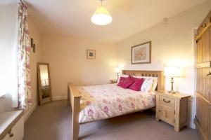 a bedroom with a bed with pink pillows at Old Quarry Cottage Coniston in Coniston