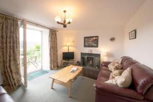 a living room with a couch and a fireplace at Old Quarry Cottage Coniston in Coniston