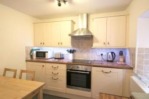 a kitchen with white cabinets and a stove top oven at Old Quarry Cottage Coniston in Coniston