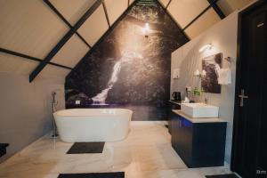 a bathroom with a large white tub and a sink at Holistic Stay Eco-Resort & Ayurvedic Retreat in Paithalmala