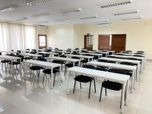 una clase con mesas y sillas blancas en una habitación en Inhambane Hotel Escola, en Inhambane