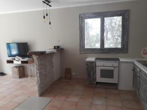 uma cozinha com um fogão, uma televisão e uma janela em Charmante maison proche Aix en pce - Spa em Ventabren