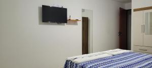 um quarto com uma cama e uma televisão na parede em Suite Pajuçara em Maceió