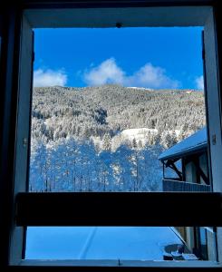 Blick auf einen schneebedeckten Berg aus dem Fenster in der Unterkunft Hôtel Restaurant Le Madame in La Ferrière