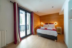 a bedroom with a bed and a large window at Hôtel Restaurant Le Madame in La Ferrière