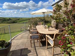 a wooden deck with a table and chairs and an umbrella at Secluded Escape near Salcombe - Newhouse Barn. in Malborough
