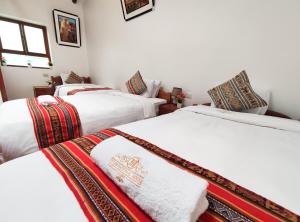 Habitación con 3 camas y toallas. en House Cusco, en Cusco