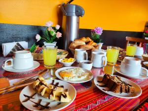 una mesa cubierta con platos de comida y bebida para el desayuno en House Cusco, en Cusco