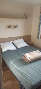 Una cama con dos almohadas blancas encima. en MOBIL-HOME Parc des Allais, en Trogues