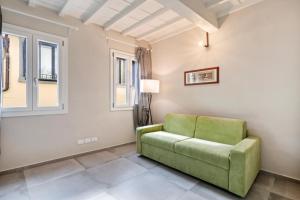 a green couch in a living room with windows at La Loggia della Signoria Charming Loft in Florence