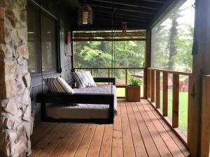 a porch with a bed on a wooden deck at Cabin at the cove at Watauga Lake in Butler