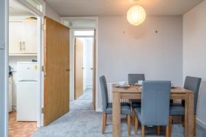 a dining room with a wooden table and blue chairs at Spacious Pet-Friendly Apartment in Crawley by Sublime Stays in Three Bridges