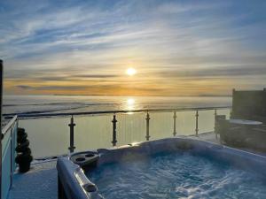 een hot tub op het balkon met uitzicht op de oceaan bij 2 Sinclair bay lodges in Keiss