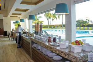 a woman standing at a buffet in a resort with a pool at Gamma Campeche Malecon in Campeche