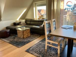 a living room with a black leather couch and a table at Haus Achterhus 215 - Wohnung 11 "Sandkörnchen" in Juist