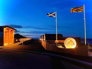 een gebouw met vlaggen en een bord 's nachts bij 3 Sinclair Bay Lodges in Keiss