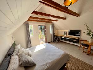ein Schlafzimmer mit einem Bett, einem Sofa und einem TV in der Unterkunft Cosy City Cottage in Gaborone