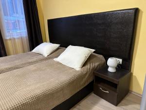 a bedroom with a large bed with a black headboard at Apartments & Rooms Royal Plaza in Borovets