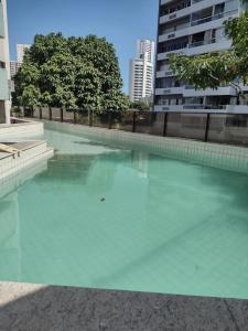 una piscina de agua verde azul en un edificio en Boa viagem vista mar 3qts, en Recife