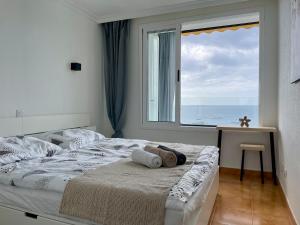 a bedroom with a bed with a large window at Direkt am Strand - Playa Patalavaca - Doñana in Patalavaca