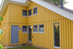 Casa amarilla con puertas y ventanas azules en Ferienhaus Mirow 66, en Mirow